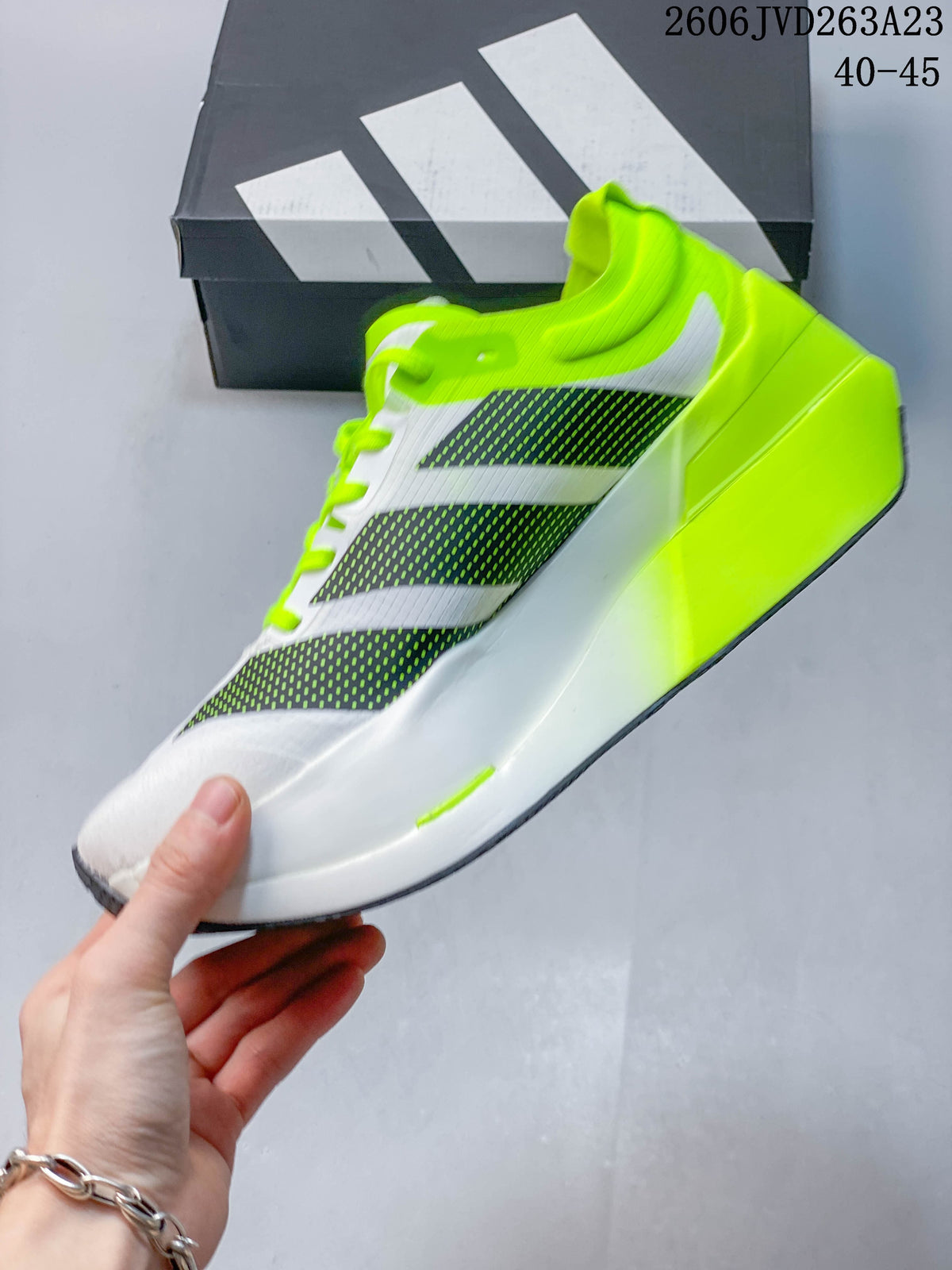 Side view of the white shoe with dark graphic panels, neon-yellow accents and raised heel.