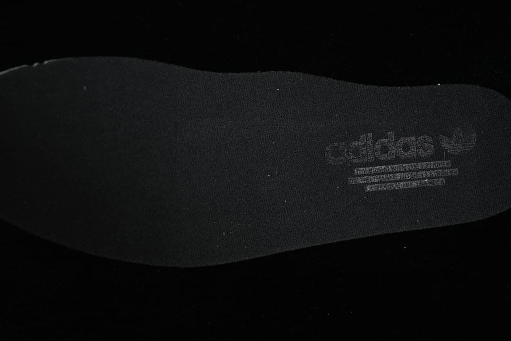 Close-up of a dark shoe insole with printed Adidas branding