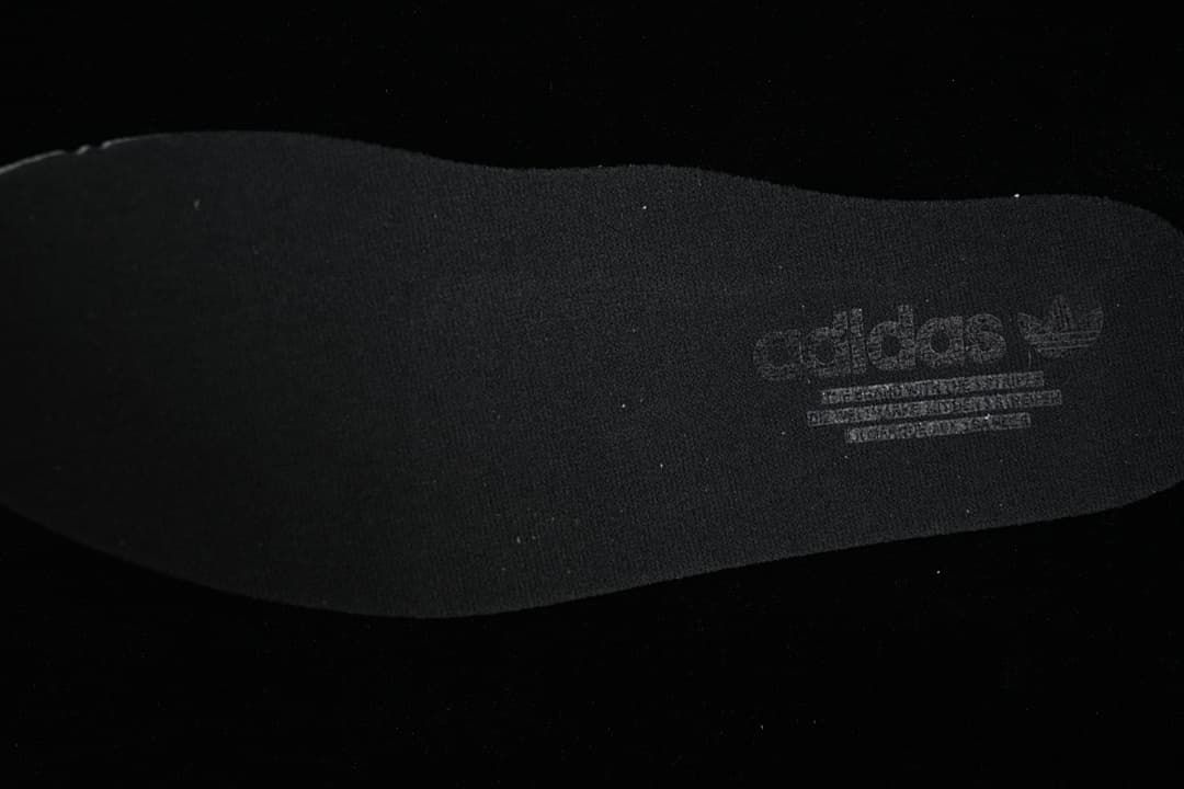 Close-up of a dark shoe insole with printed Adidas branding