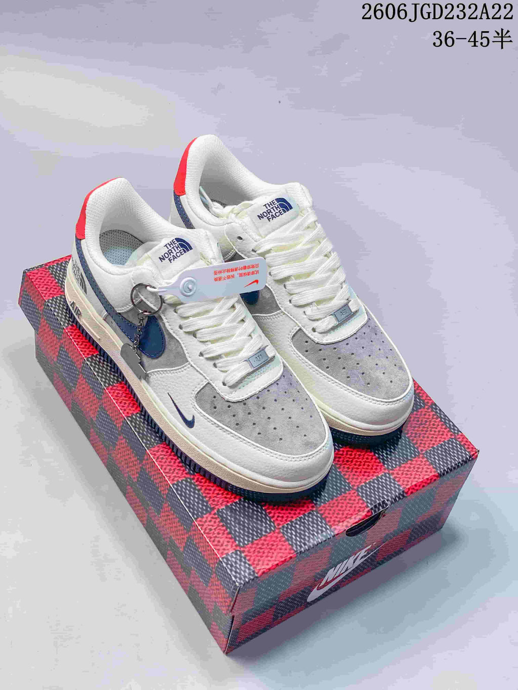Pair of white, grey and blue low-top sneakers with red heel tabs, displayed on a patterned box.