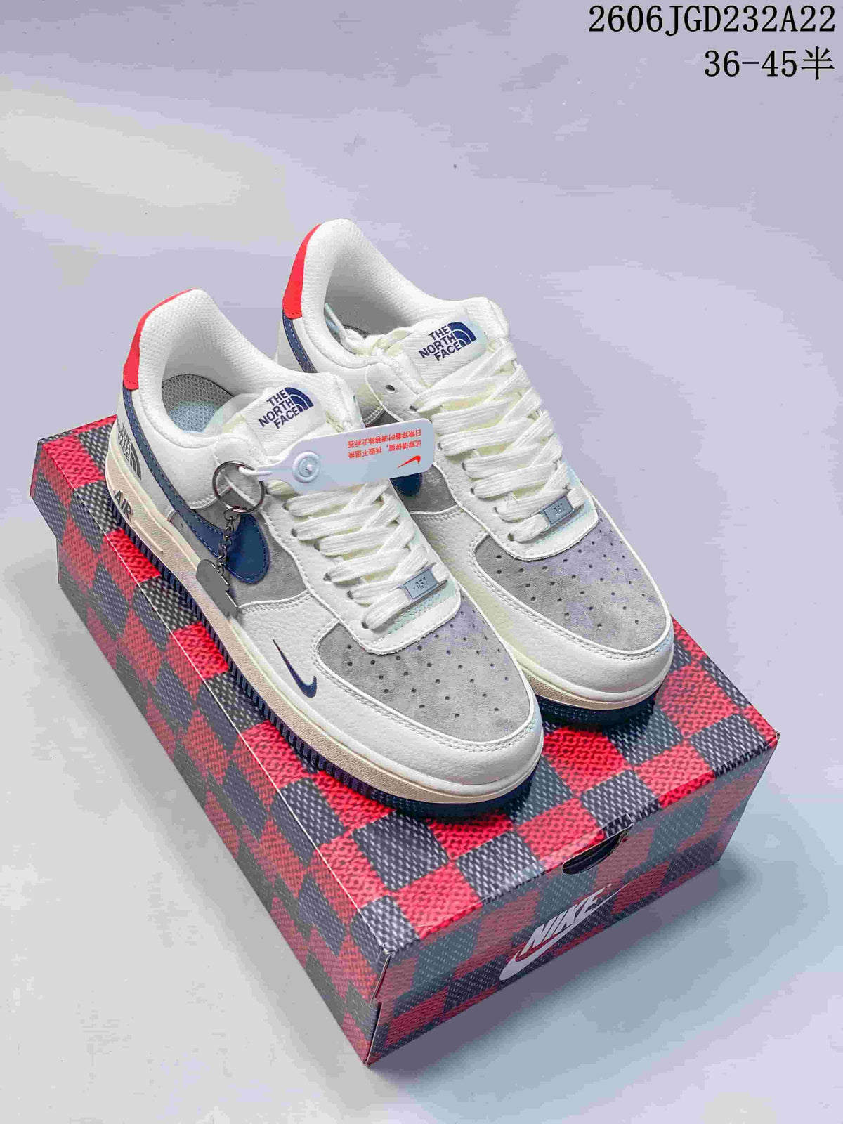 Pair of white, grey and blue low-top sneakers with red heel tabs, displayed on a patterned box.