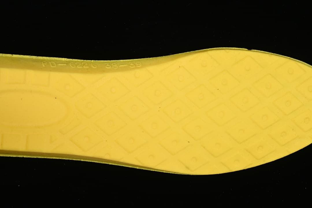 Yellow boot insole viewed from below with a molded geometric pattern
