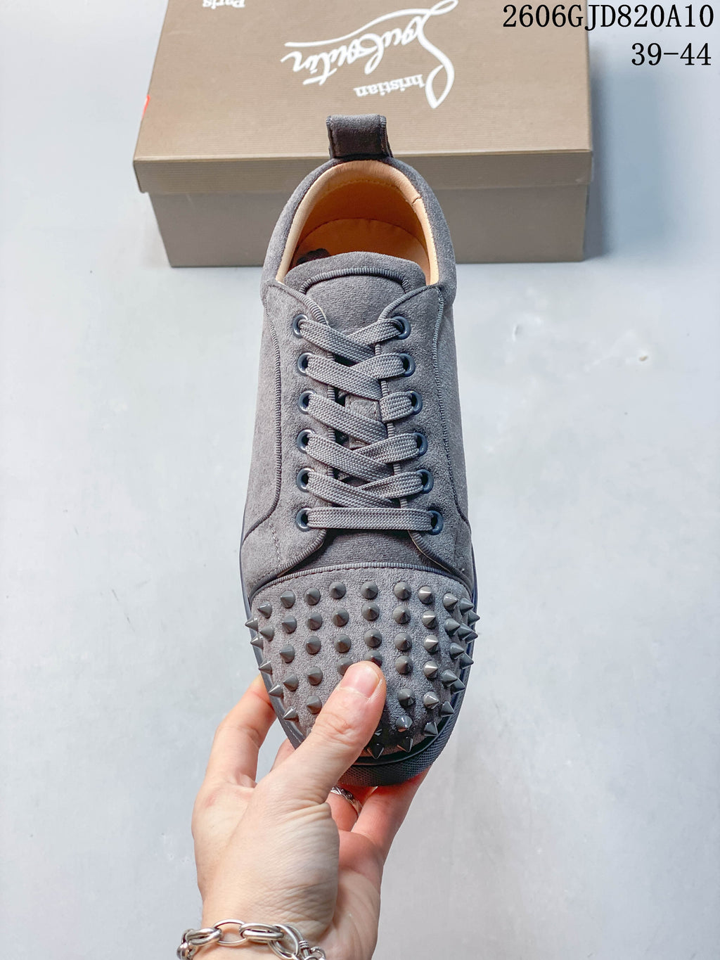Front view of a grey lace-up sneaker with studded toe detailing
