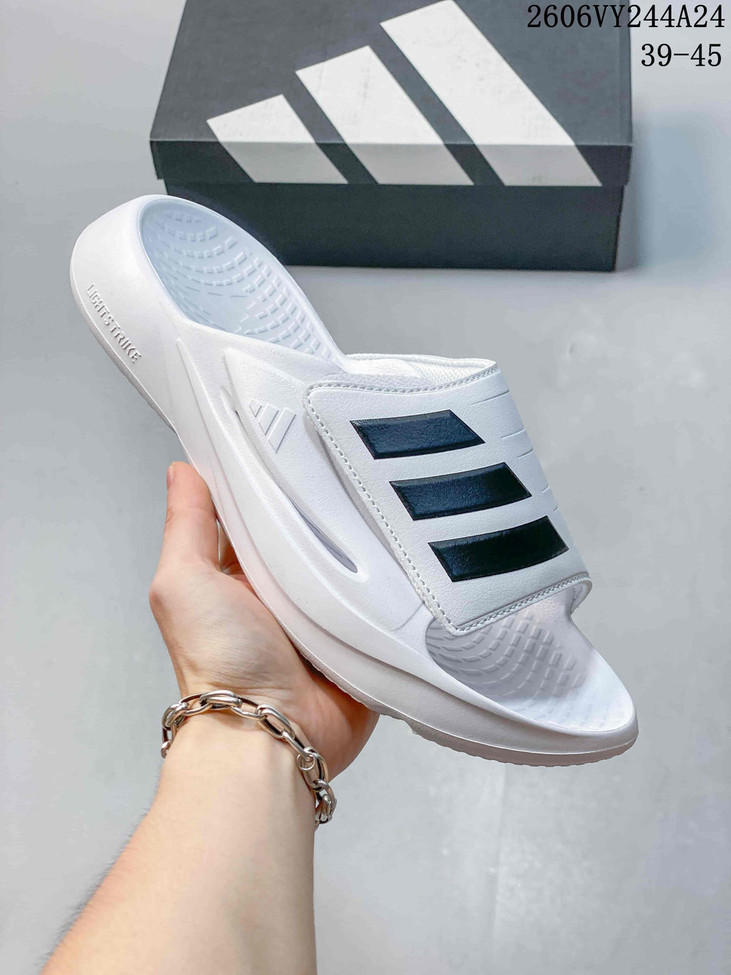 White adidas Lightblaze slide with black three-stripe detailing; image overlay lists sizes 39–45.