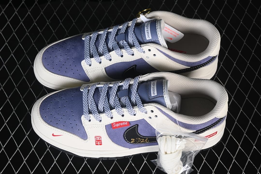 Overhead view of a pair of blue and white low-top sneakers with patterned laces and an extra pair of white laces.