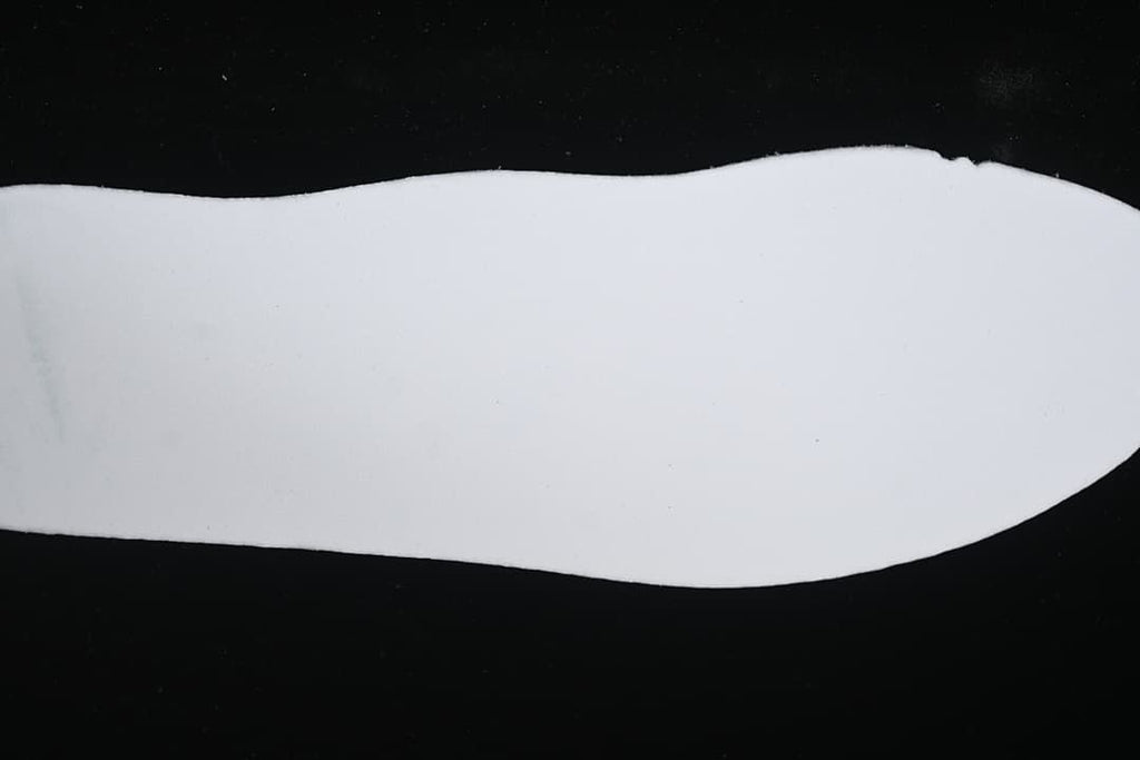 Plain white shoe-shaped piece displayed against a dark background