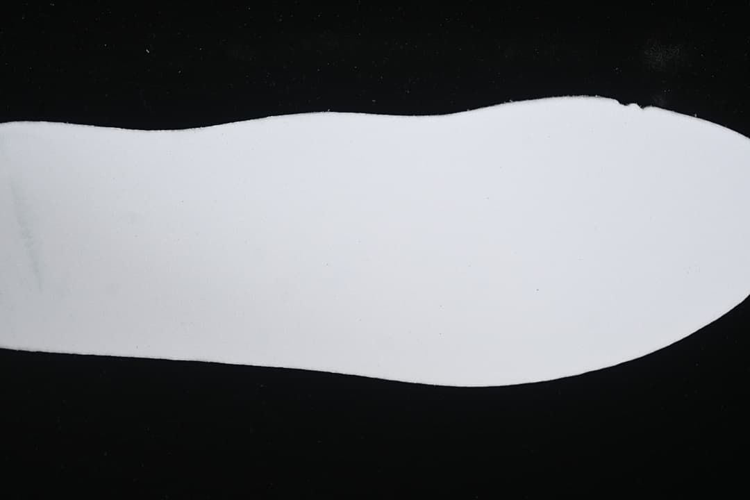 Plain white shoe-shaped piece displayed against a dark background