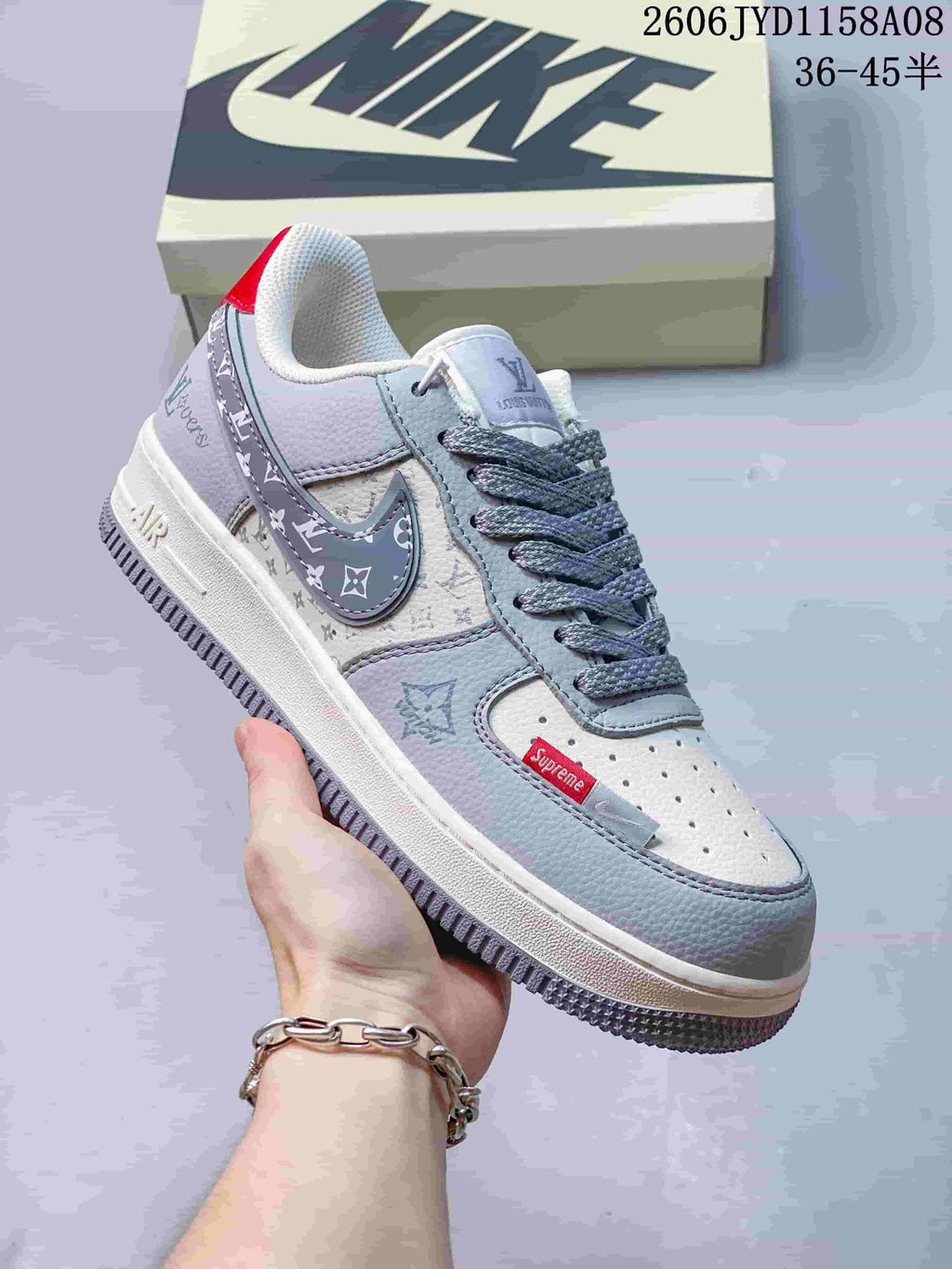 Angled side view of a gray and white sneaker with patterned panels and red accents