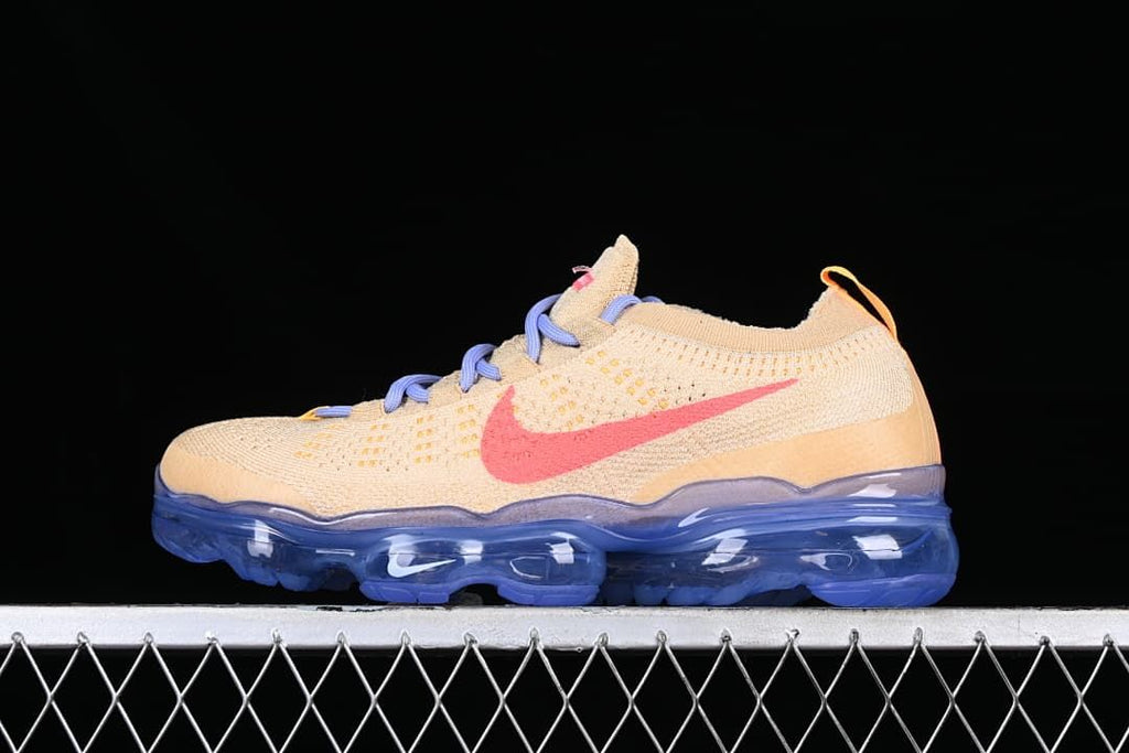 Side profile of the beige sneaker with coral-pink Swoosh, lavender laces and blue sole.