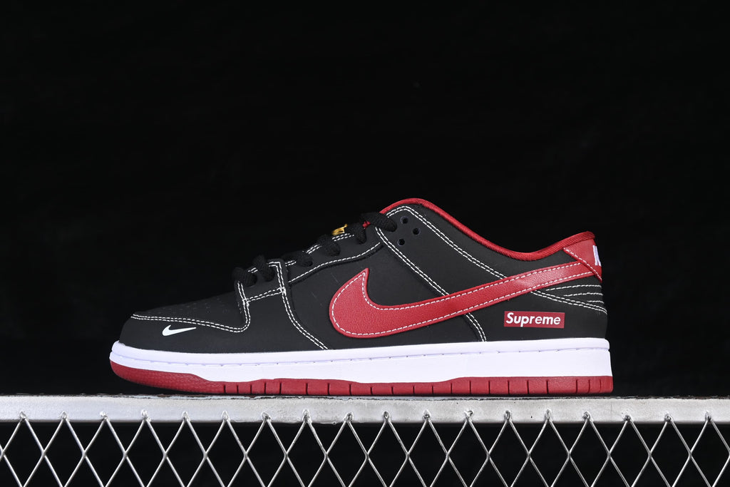 Side view of a black and red Nike SB Dunk Low sneaker with a red Swoosh, white midsole, and red outsole
