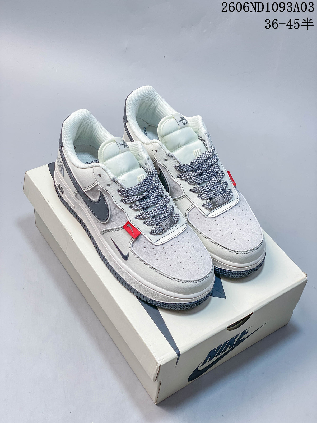 Pair of white and gray sneakers shown from the front on a shoebox