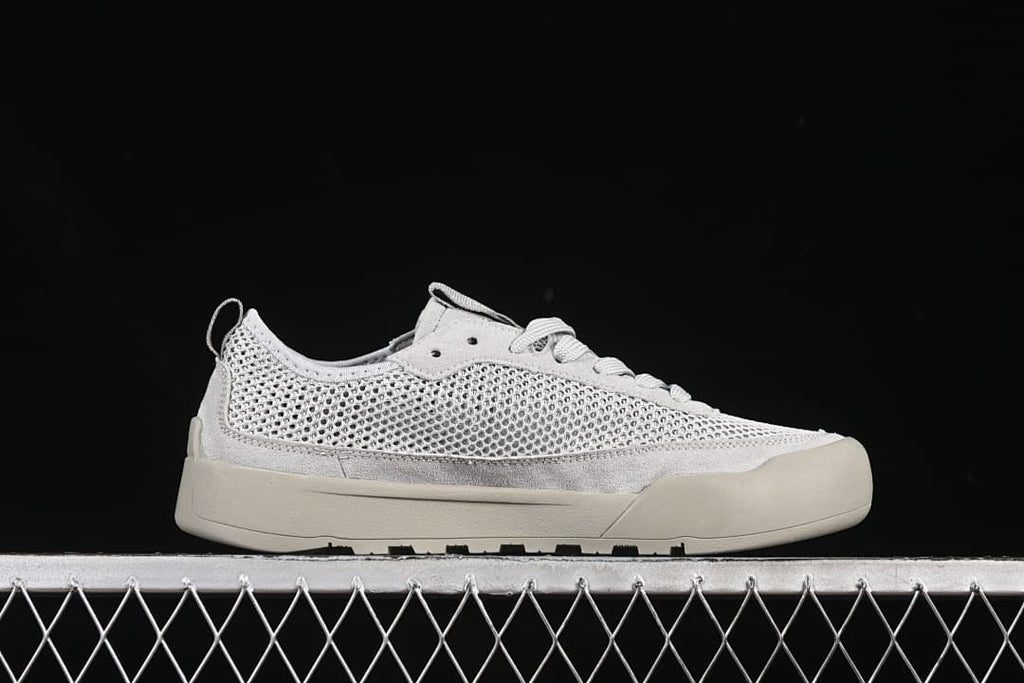 Side profile of the grey low-top sneaker with mesh-style upper and thick sole.