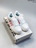 Pair of white adidas Entrap sneakers with pink stripes displayed on a shoebox