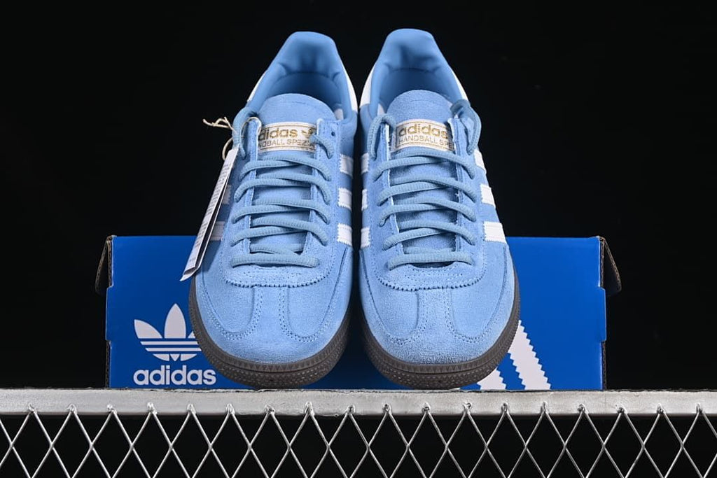 Front view of the blue and white lace-up sneakers on a blue box