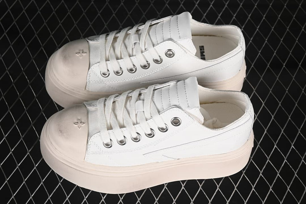 Pair of white low-top sneakers with pale platform soles, shown from the side.