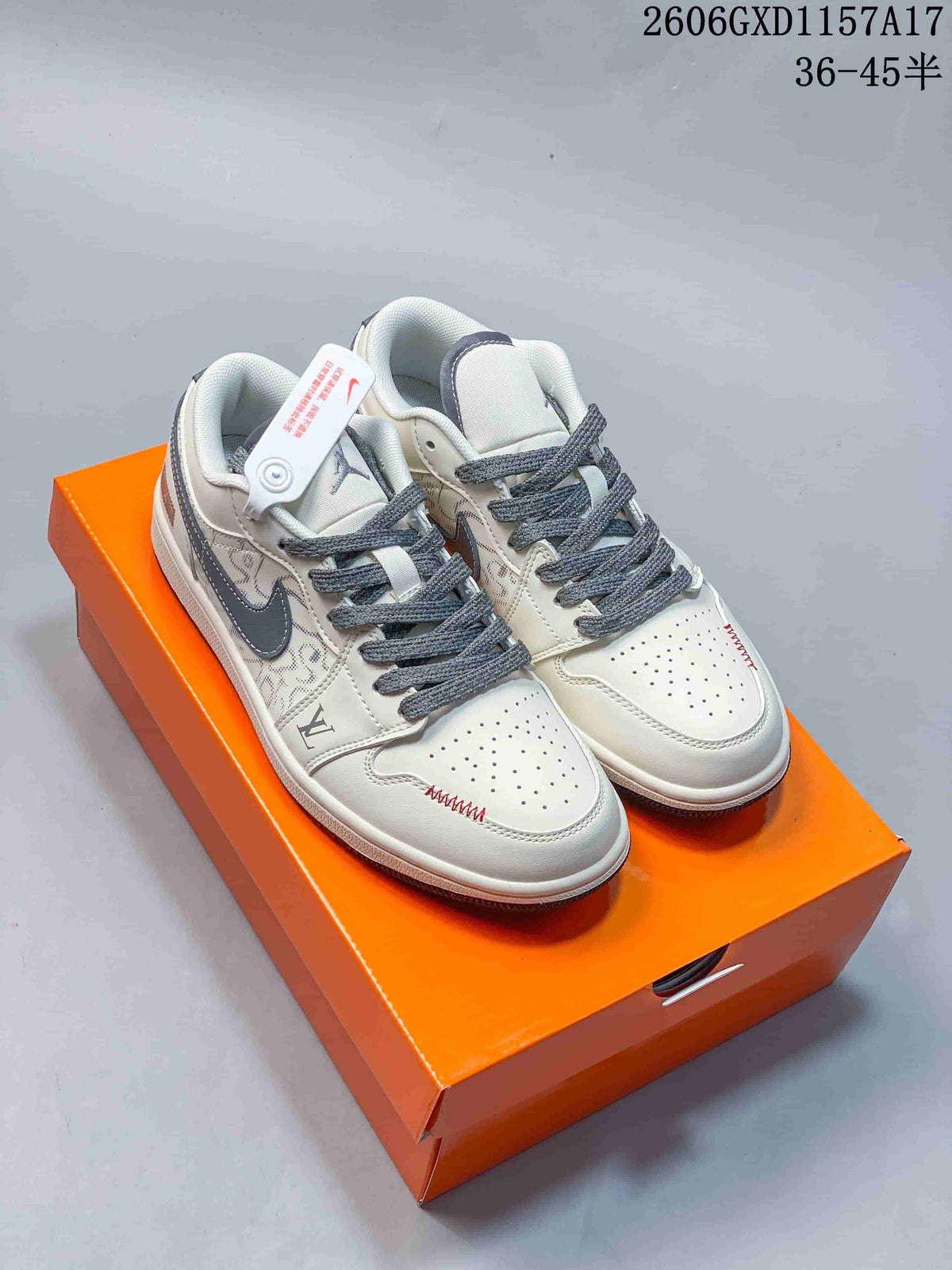 Pair of cream and grey Jordan 1 low-top sneakers with patterned side panels and red stitching, shown on an orange box