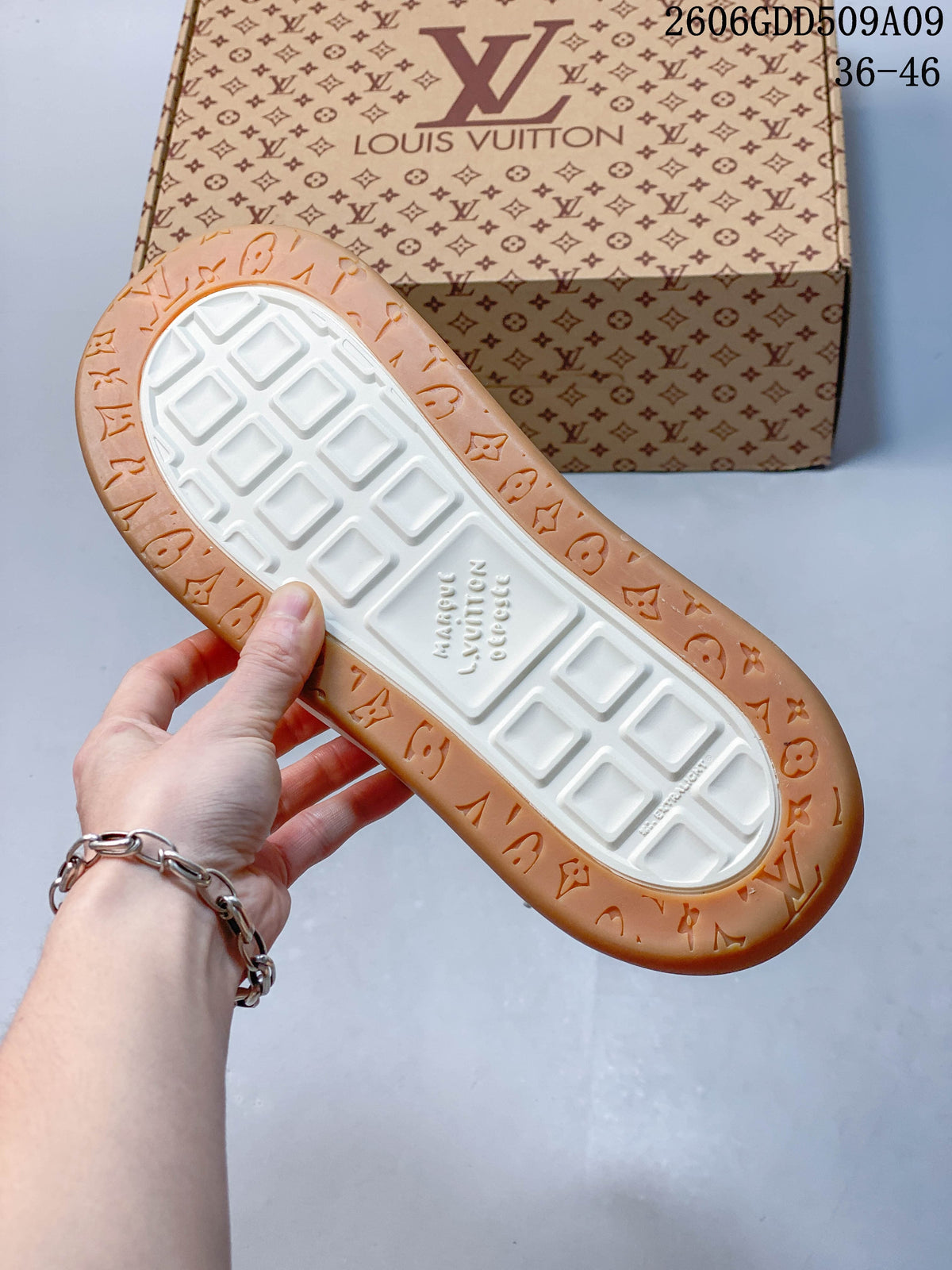 Underside of sneaker showing a white tread center and tan patterned outsole edge.