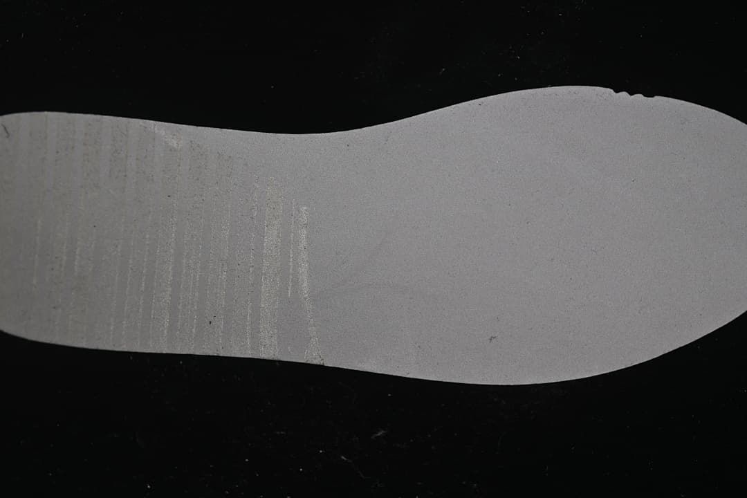 Underside of the sneaker midsole shown against a dark background