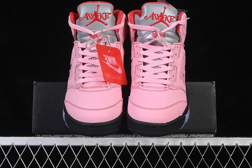 Front view of the pink sneakers showing the laces, tongues, and contrasting dark soles.