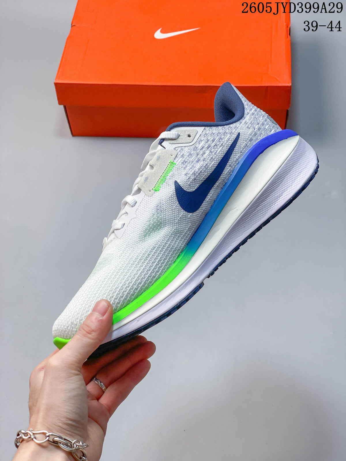 Side profile of a white and light gray Nike Air Zoom Vomero 17 shoe with navy and bright green accents.