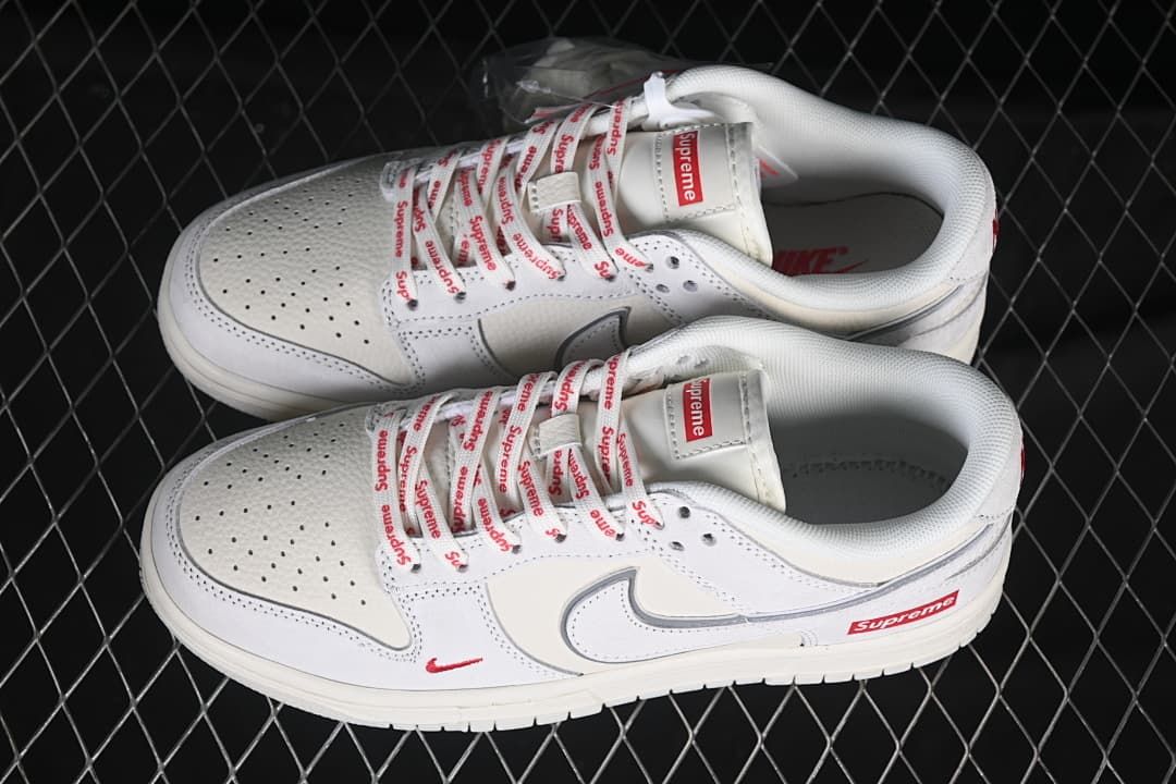 Top view of a pair of white and grey Nike SB Dunk Low sneakers with Supreme-branded laces