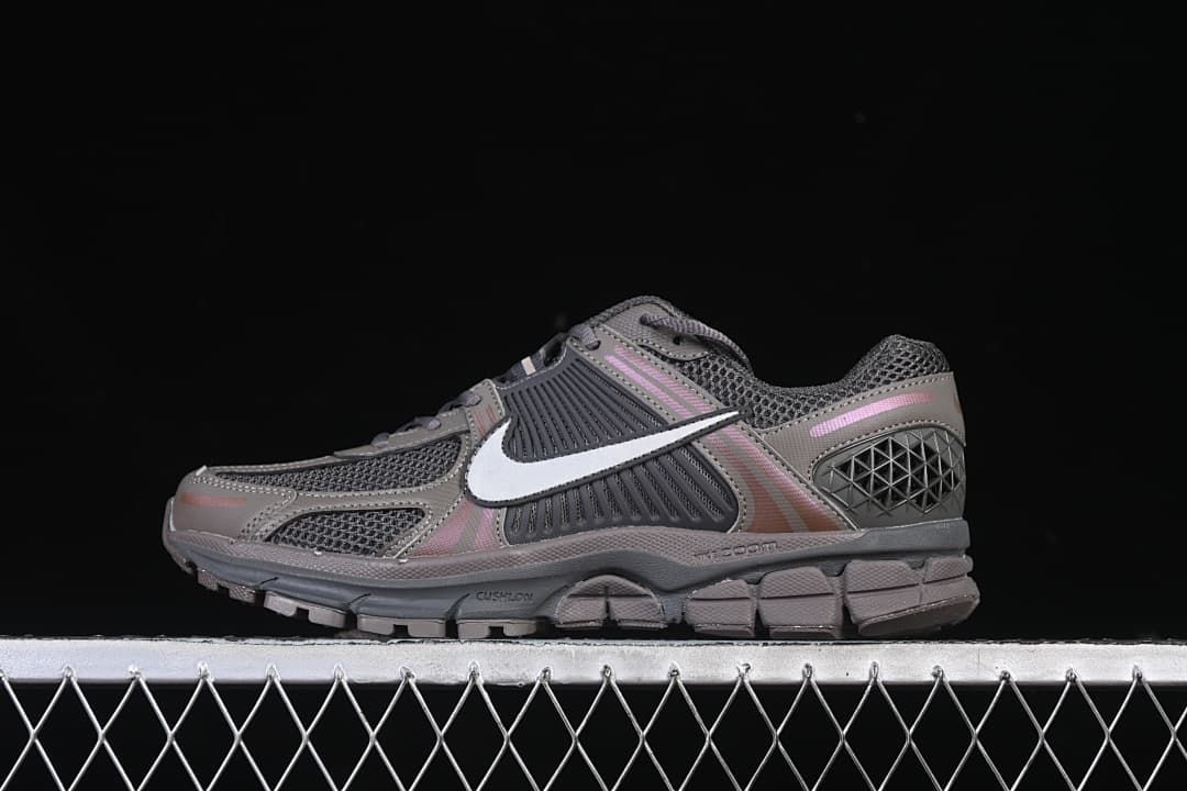 Side view of dark grey Nike Zoom Vomero 5 sneakers with white Swoosh and pink accents