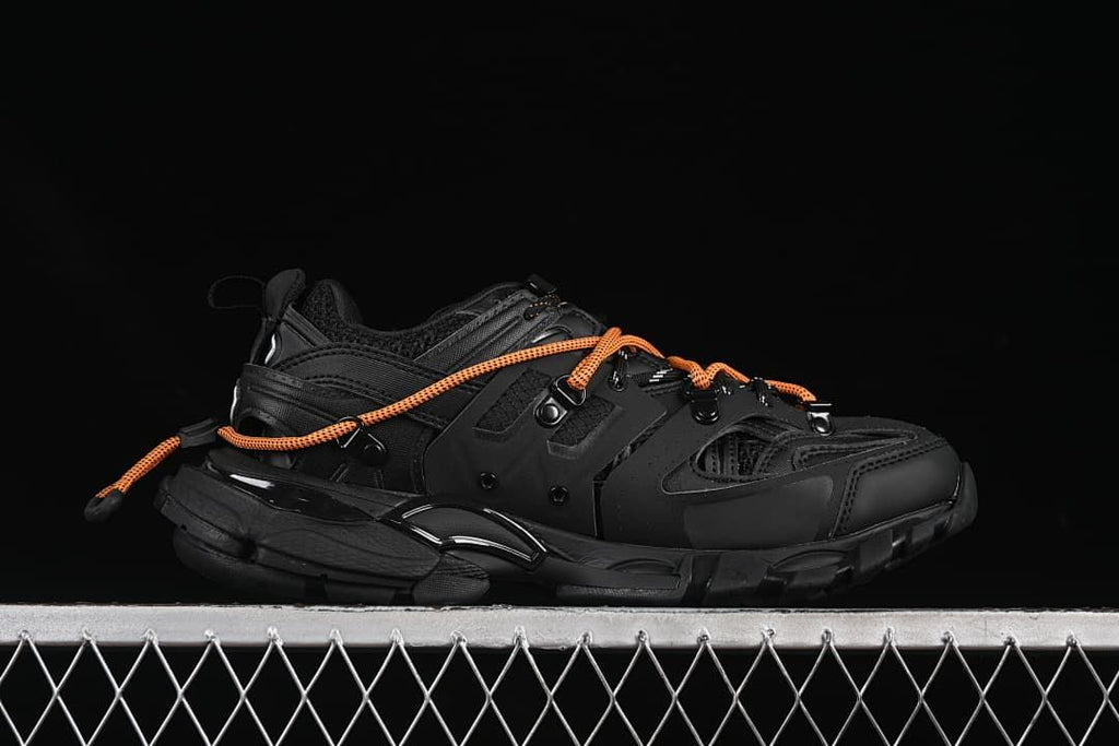 Side profile of a black sneaker with orange laces.