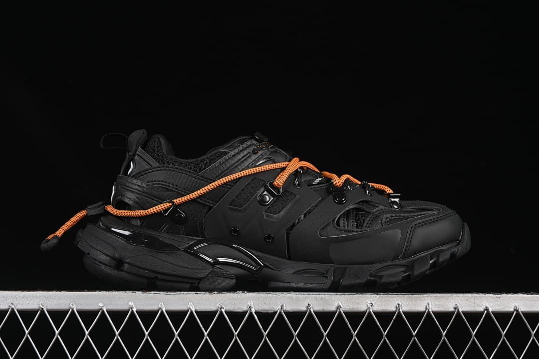Side profile of a black sneaker with orange laces.