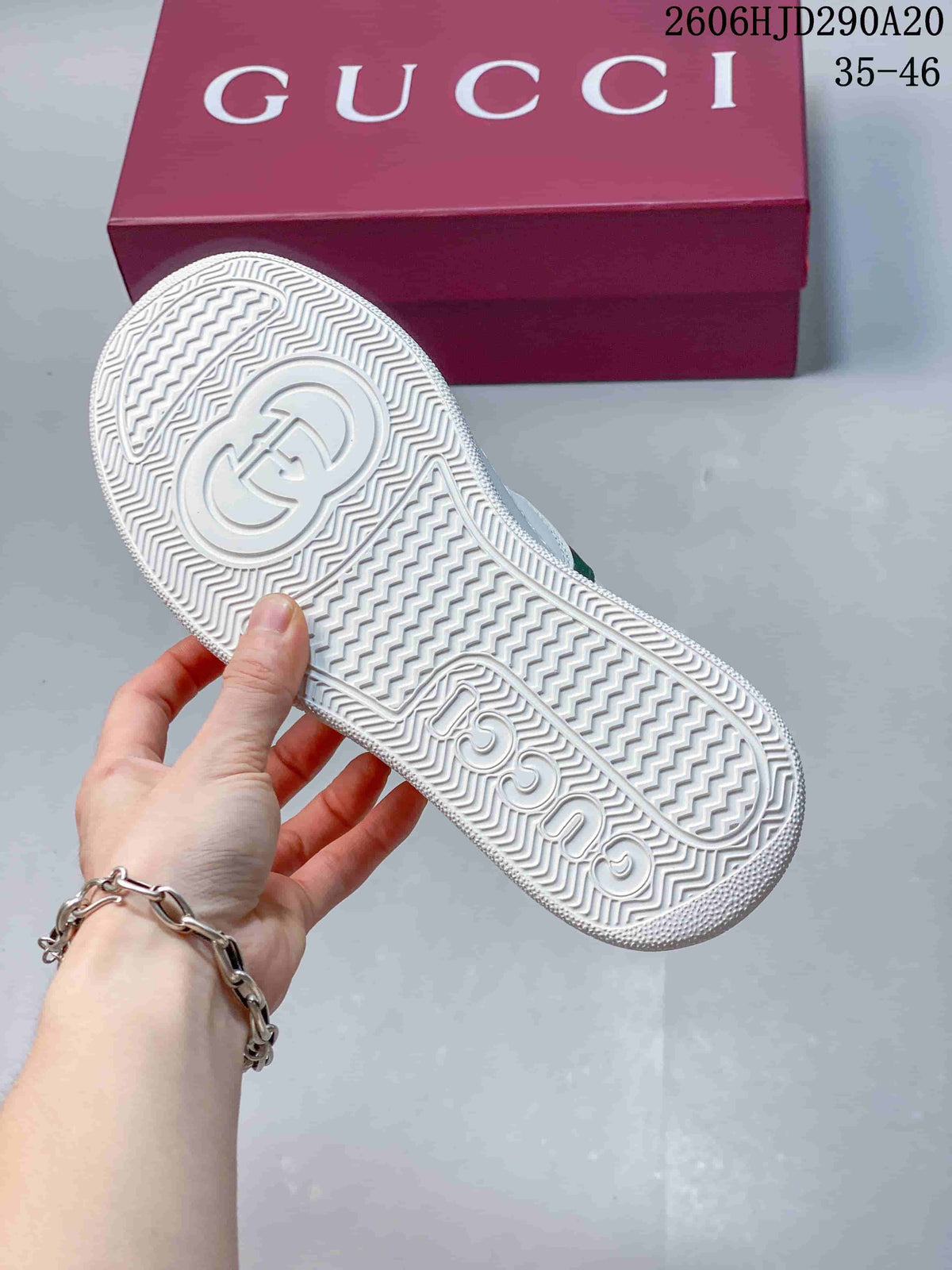 Underside of the white sneaker showing a patterned tread and embossed branding