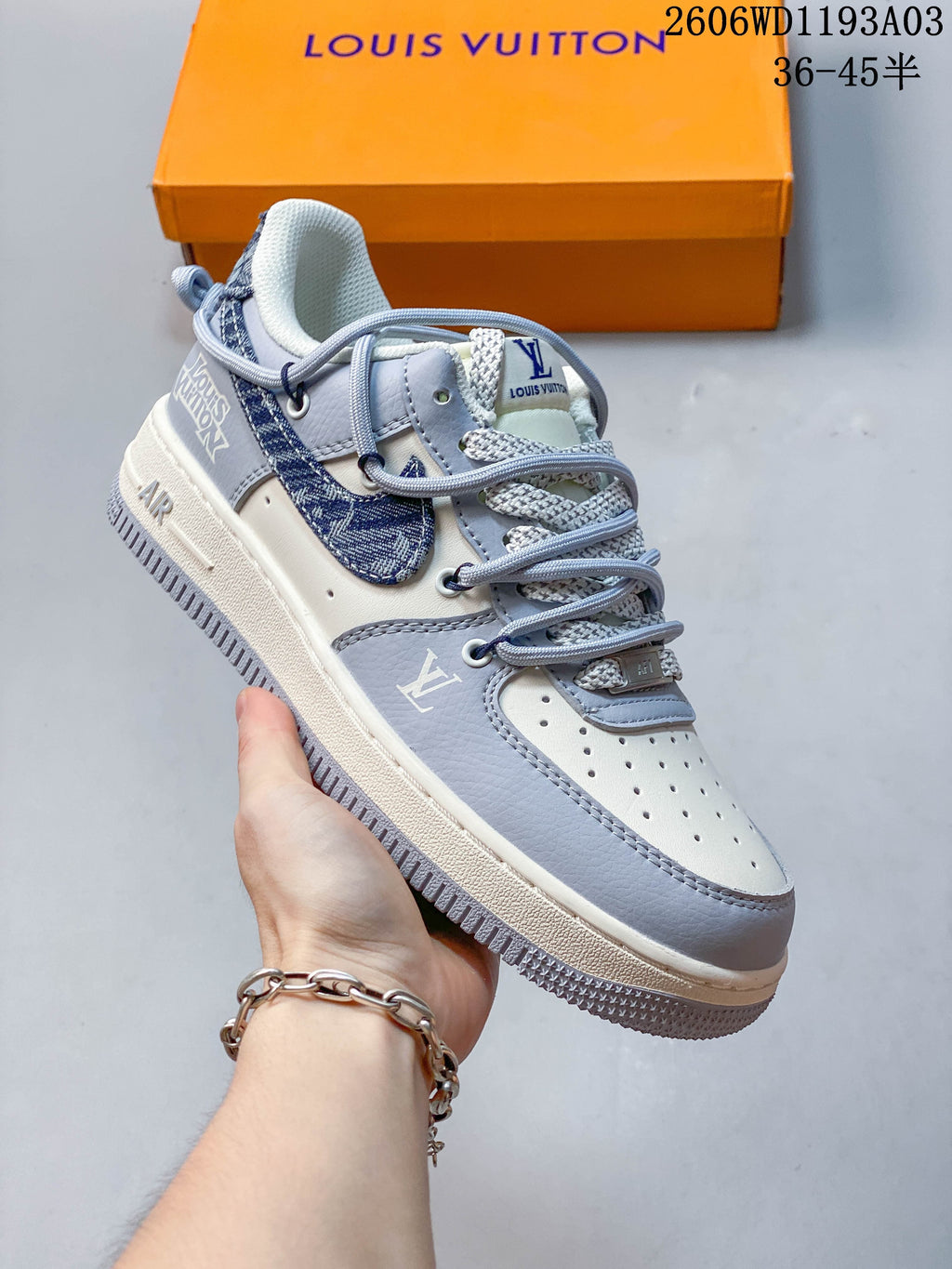 Angled side view of the white and gray sneaker with blue patterned side panel, layered laces, and contrasting sole.