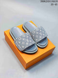 Pair of gray monogram-patterned open-toe slide sandals on an orange box