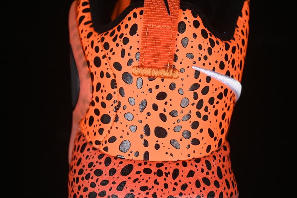 Rear close-up of orange and black spotted upper with heel pull loop.