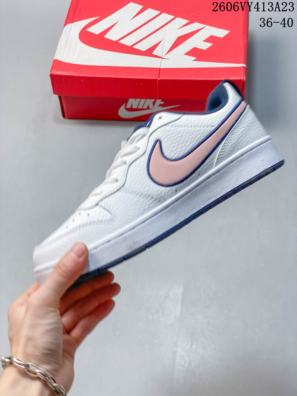 Side view of a white NikeCourt Borough 2 Low sneaker with a pink Swoosh and navy trim