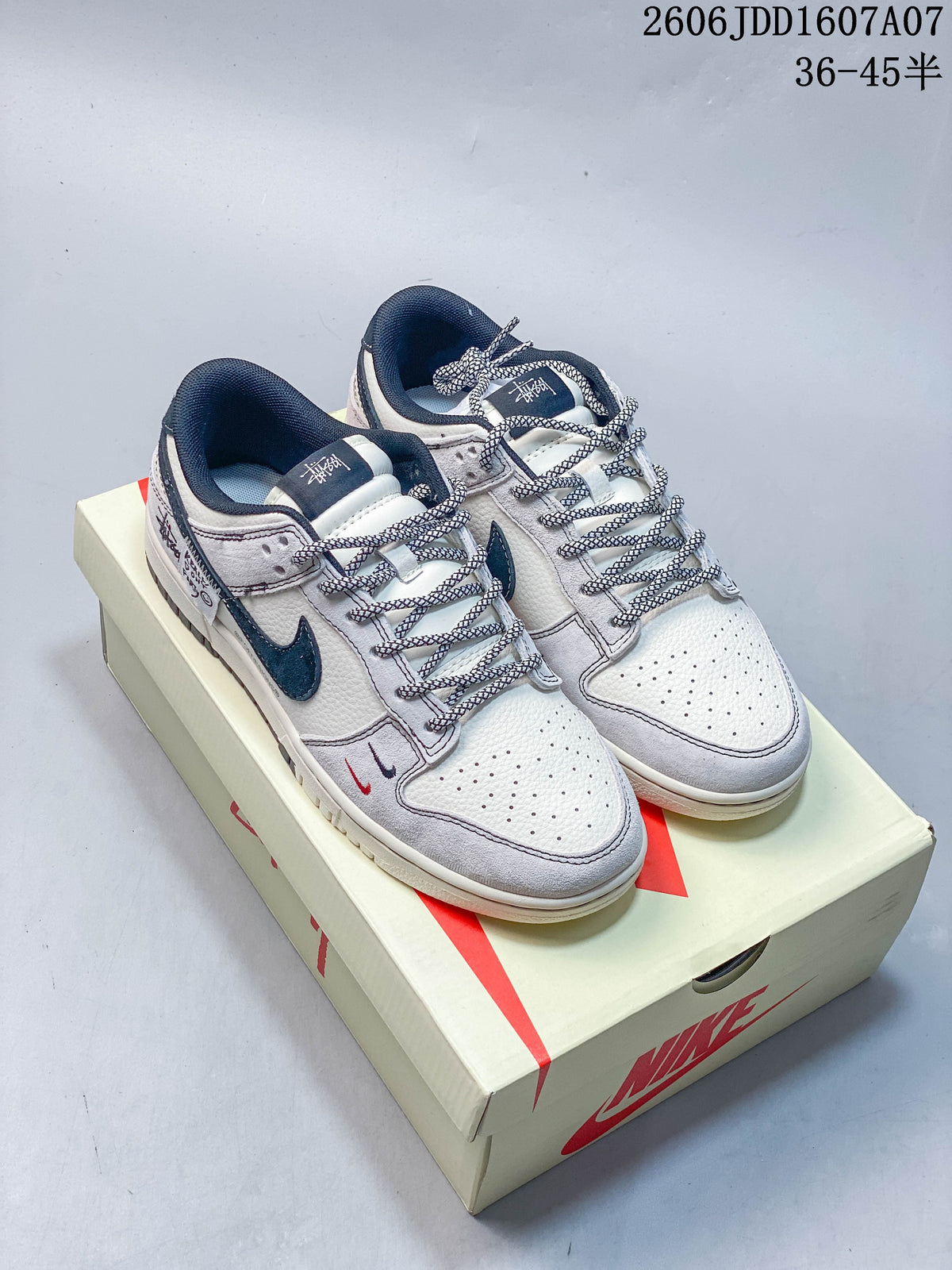 Pair of grey and white low-top sneakers with dark blue accents and patterned laces.