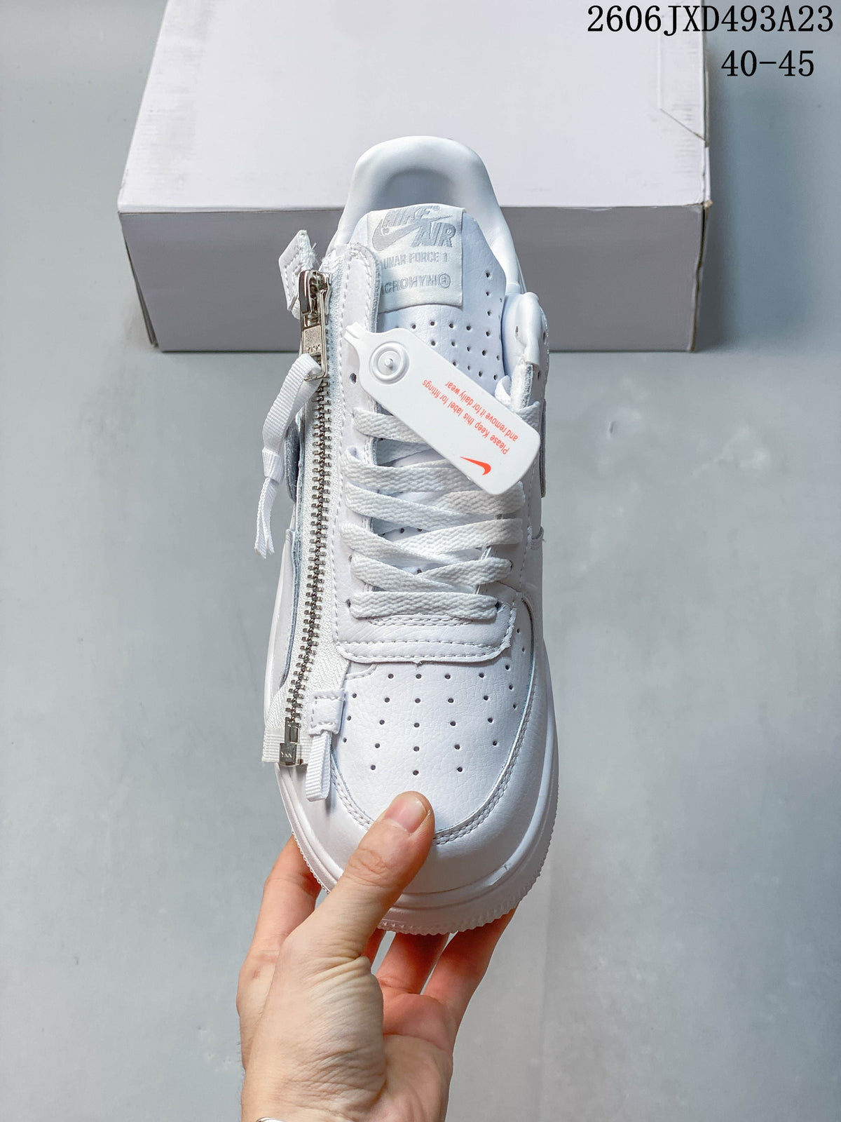 Front view of the white sneaker showing perforated toe and side zipper