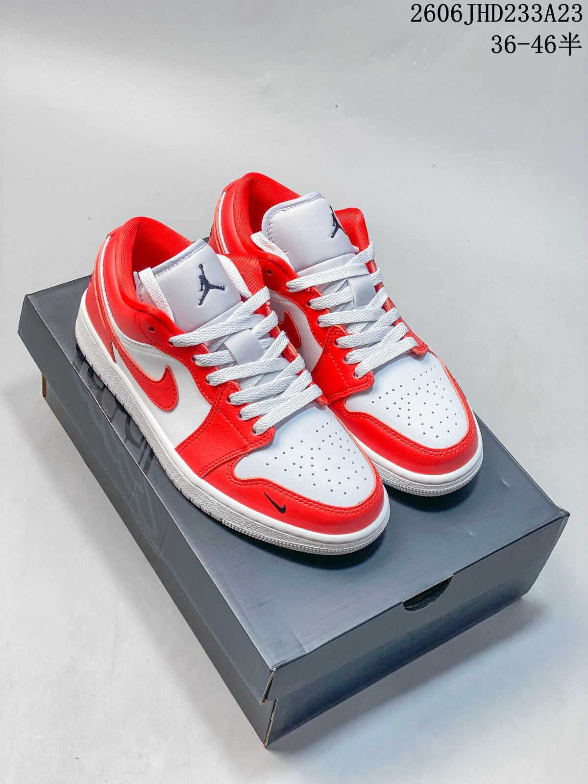 Pair of red and white low-top Air Jordan 1 sneakers on a dark shoe box