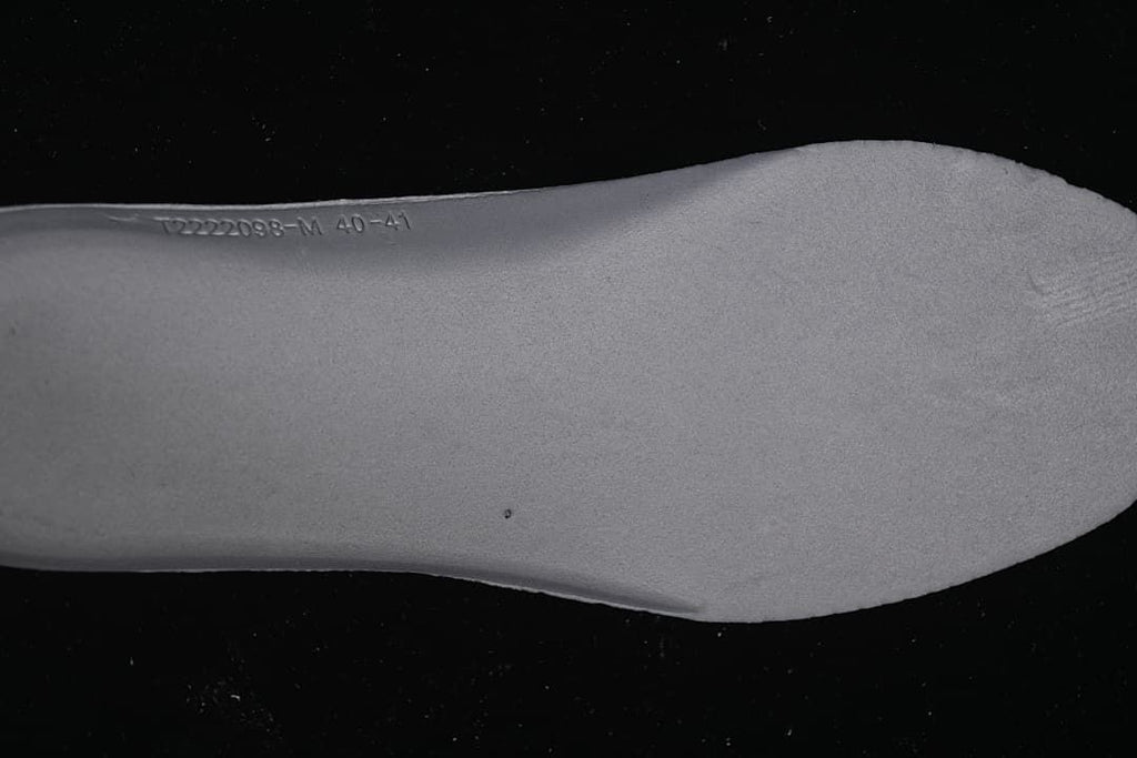 Light-colored shoe insert with stamped markings