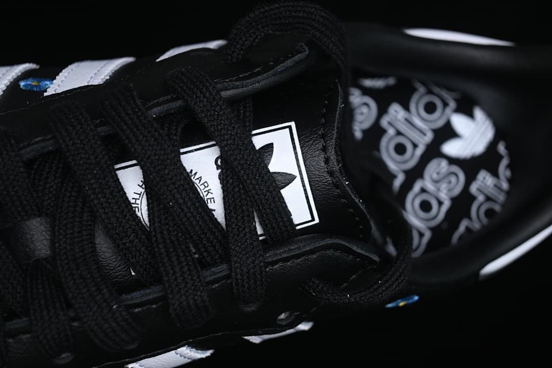 Close-up of black laces and branded tongue label with patterned insole behind