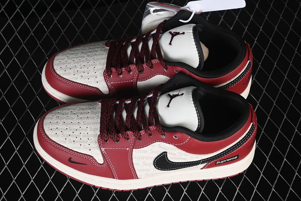 Pair of red, black, and white Air Jordan 1 Low sneakers shown from above, with patterned white panels and dark red laces.