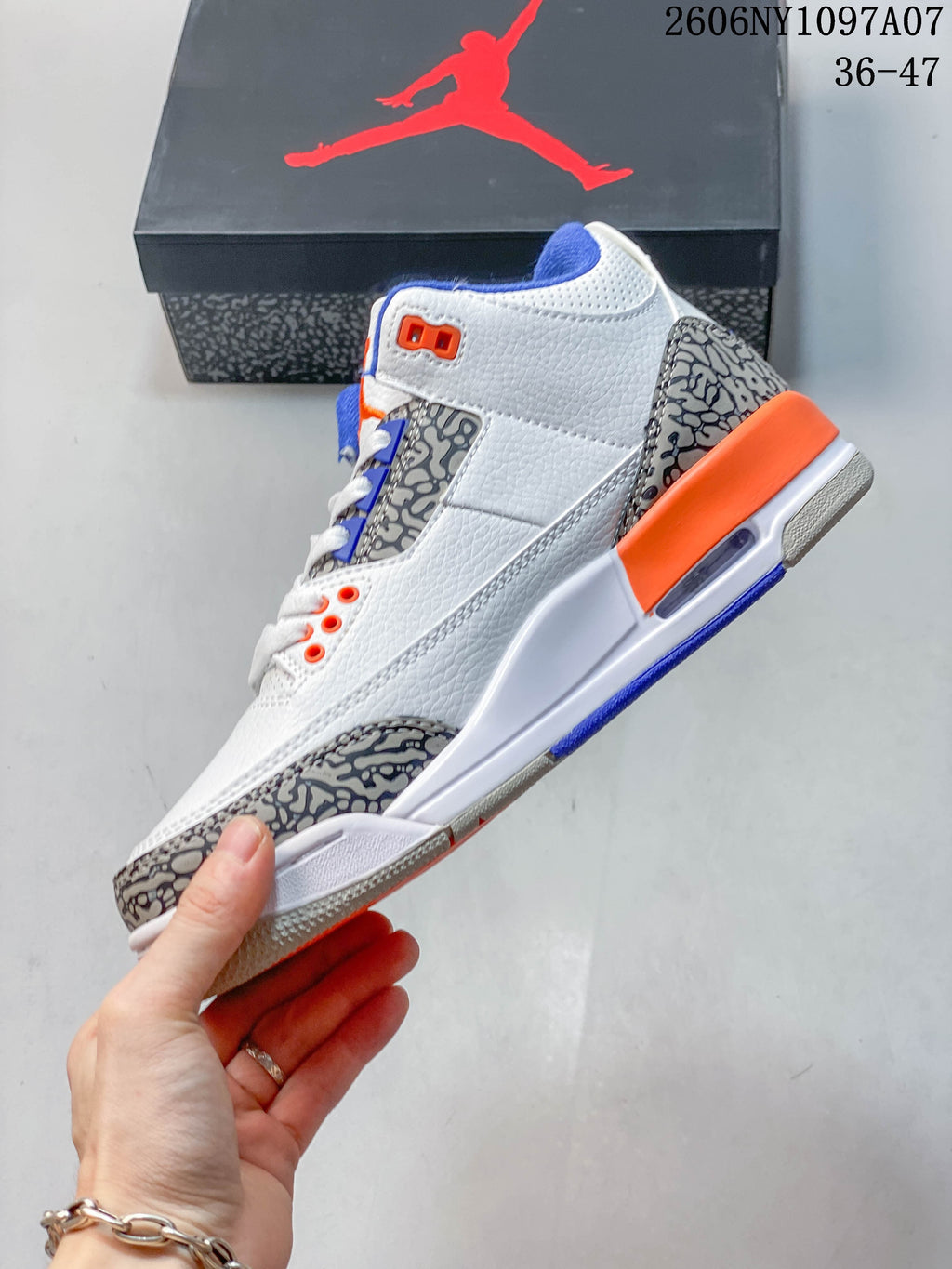 Side view of the white Jordan Air Jordan 3 Knicks sneaker with elephant-print panels and orange and blue accents