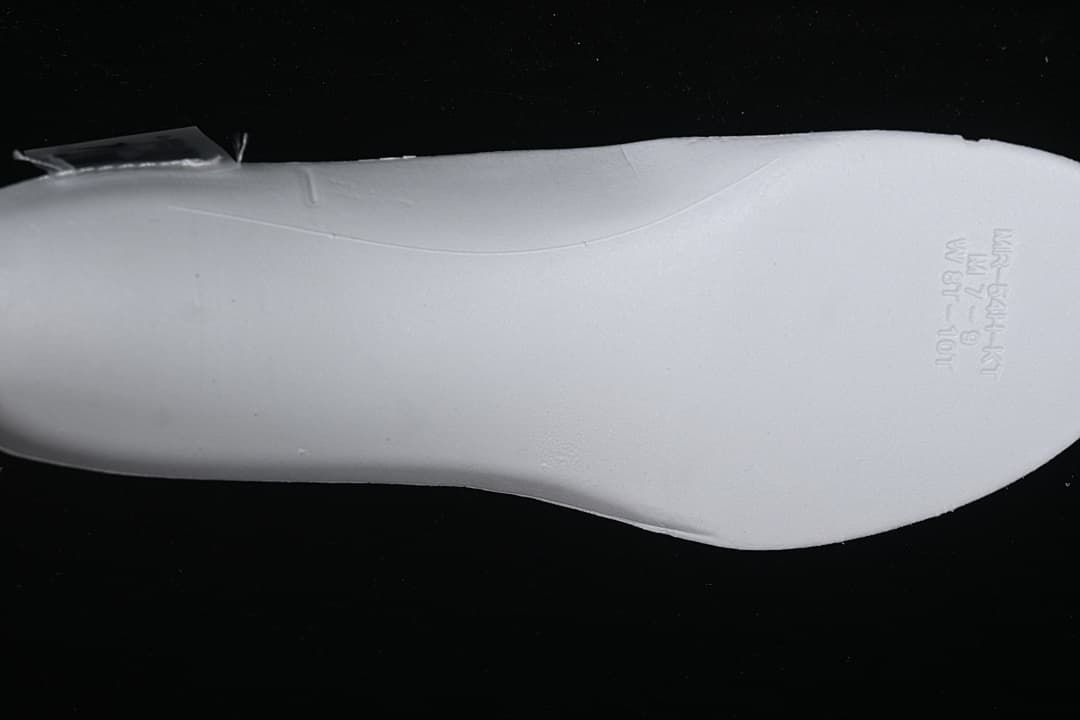 Underside view of the white shoe's insole with printed markings