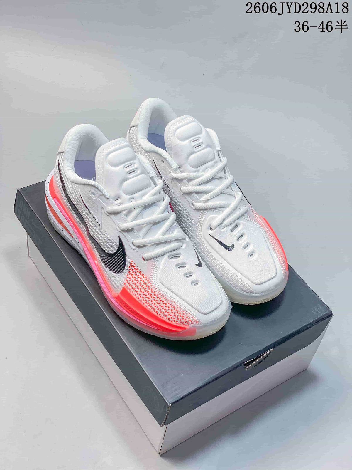 Pair of white Nike Air Zoom GT Cut low-top shoes with black Swooshes and coral accents, shown on a shoe box