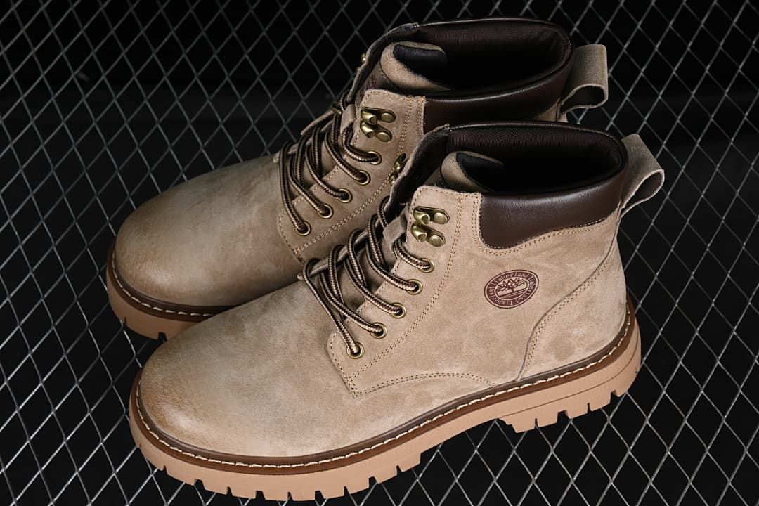 Pair of khaki mid-top lace-up boots showing dark collars and chunky lugged soles.