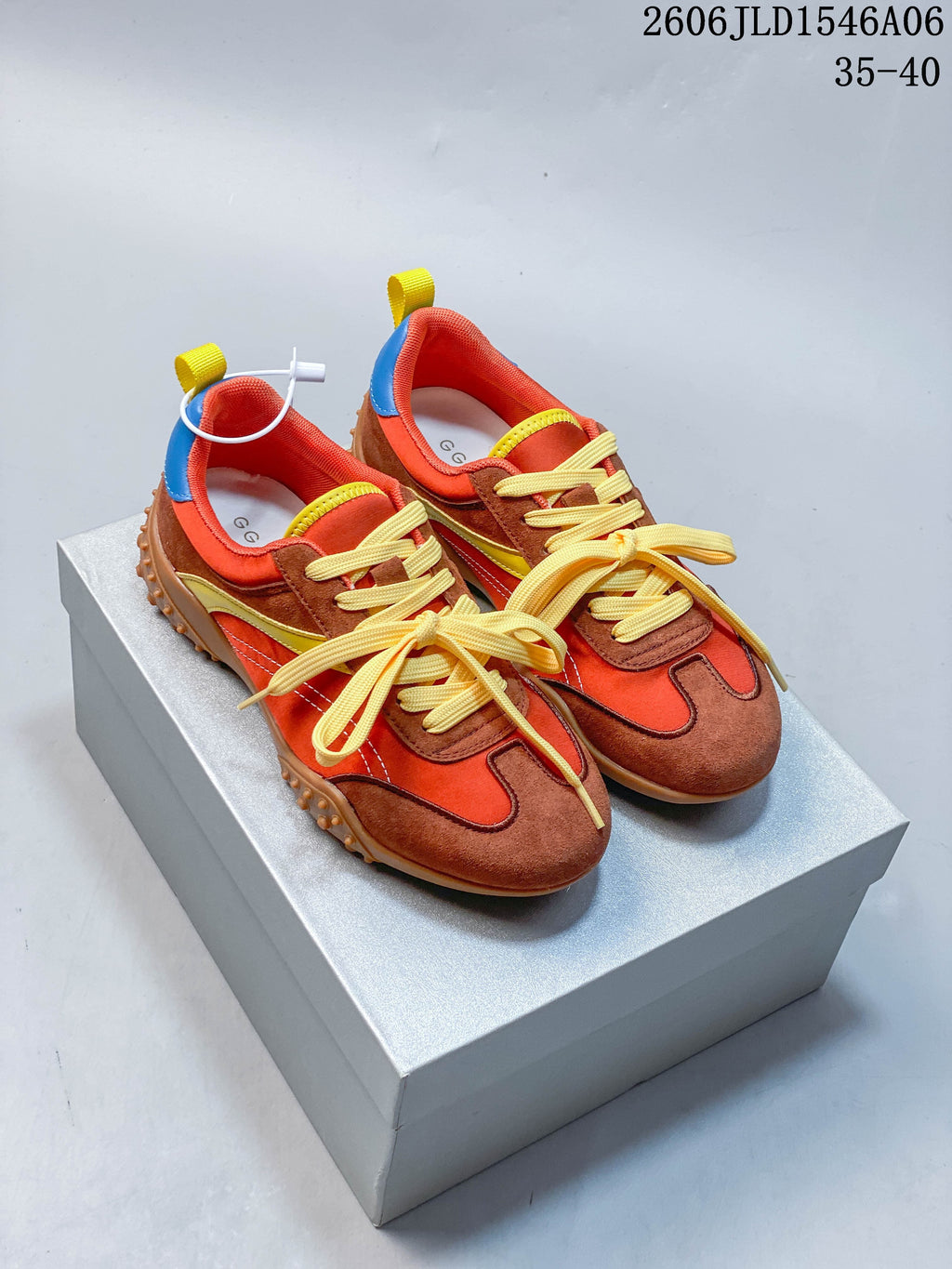 Pair of orange and brown color-block low-top sneakers with yellow laces and textured gum-colored outsoles