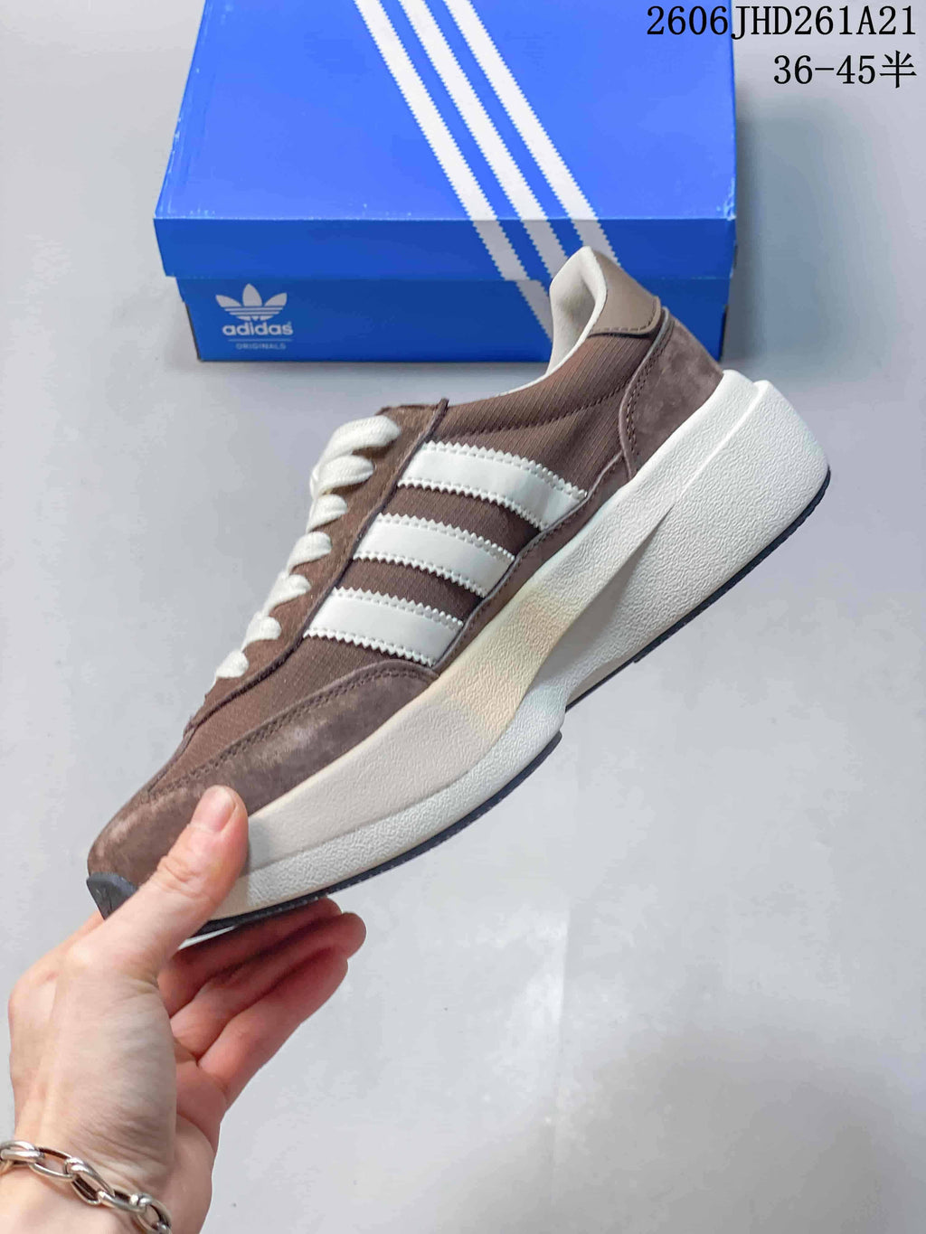 Side profile showing the taupe upper, white stripes, and raised midsole