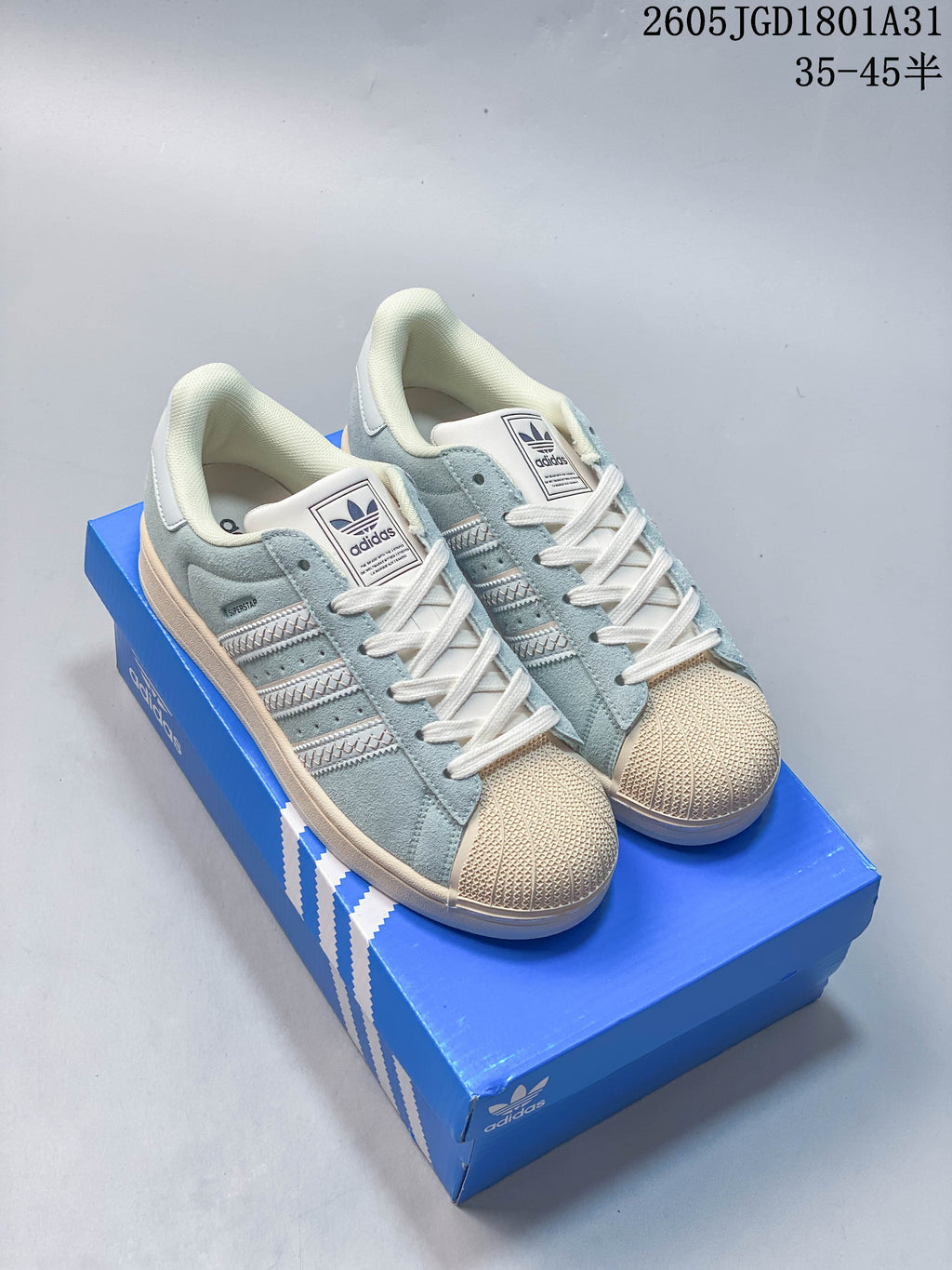 Pair of light blue and cream adidas Originals Campus 00s sneakers on a blue shoebox