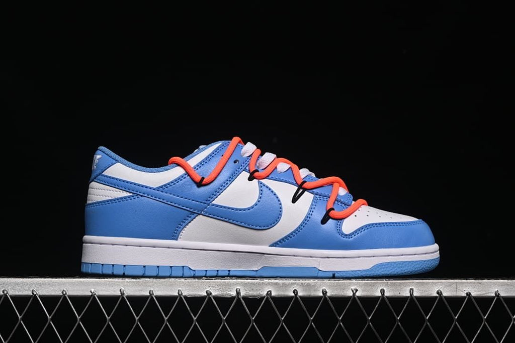 Side profile of a blue and white low-top sneaker with orange-red overlay laces.