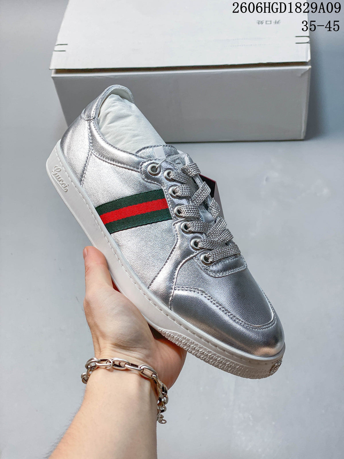 Angled view of a silver low-top sneaker with a green-and-red side stripe.