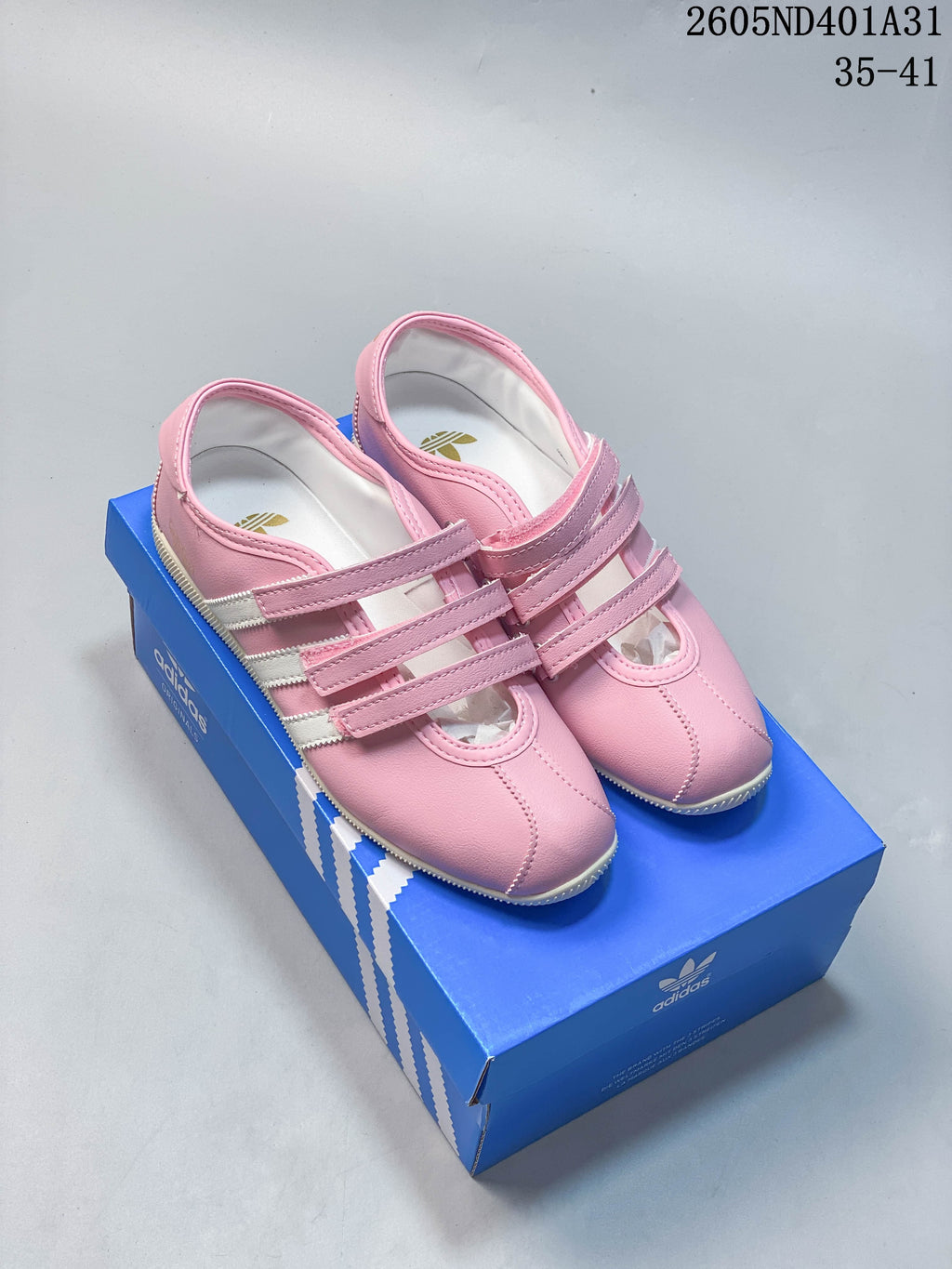 Pair of pink Adidas Samba Vegan OG strap sneakers on a blue box