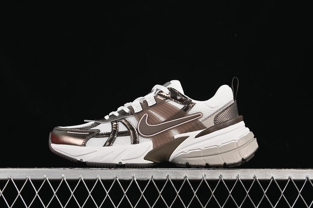 Side view of a white Nike V2K Run sneaker with brown and metallic bronze-colored details